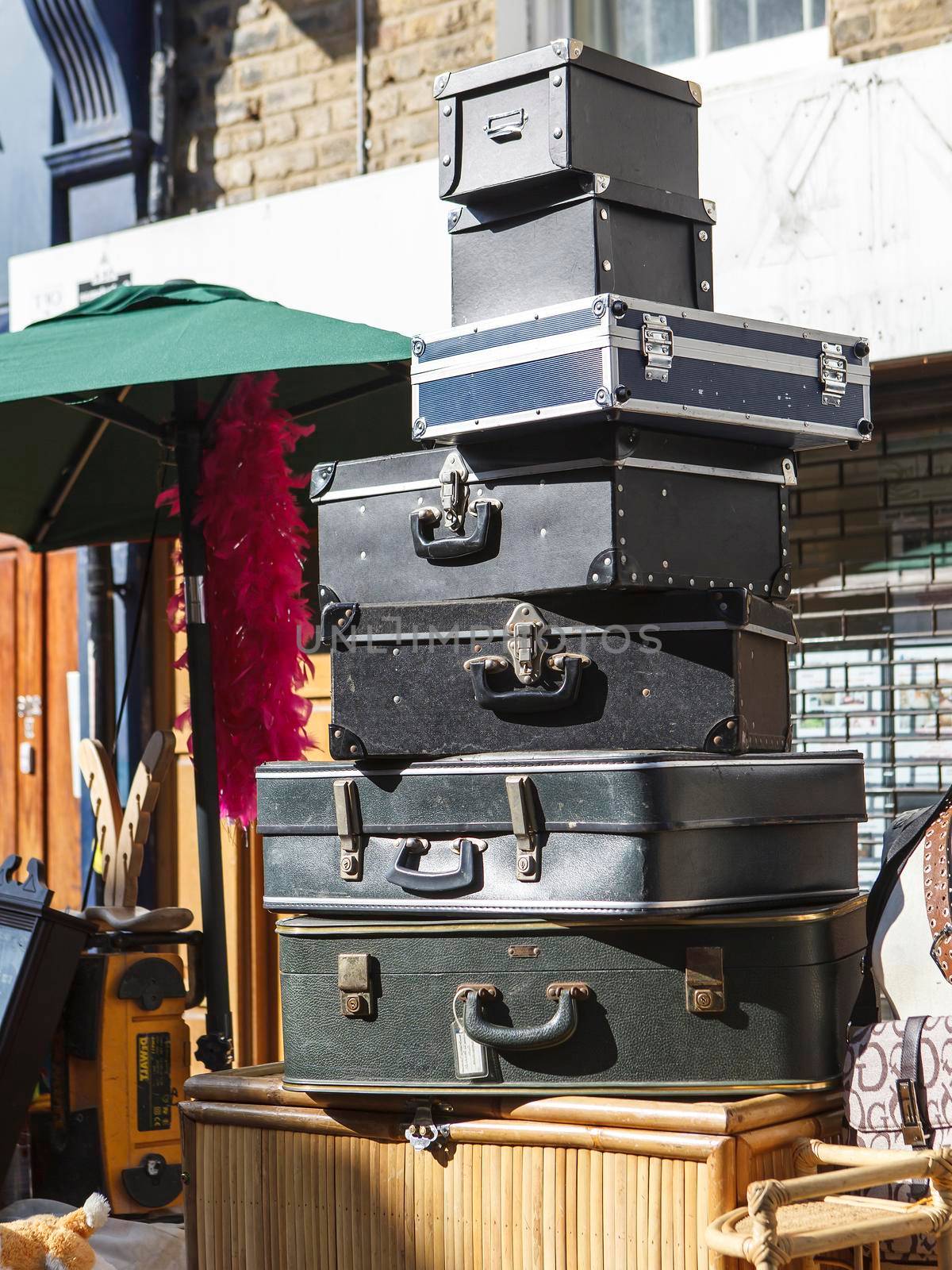 A pile of suitcases stacked in a pyramid on a table at a brick lane Sunday street market by elenarostunova