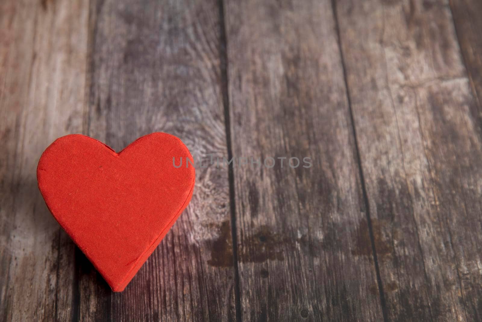 The red paper heart is on a wooden brown table. The day of Valentine. Copy space