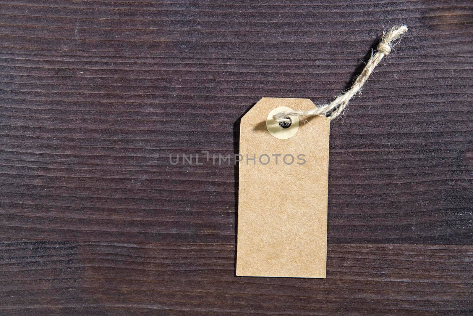 Blank white tag with string on wooden brown background. Copy space