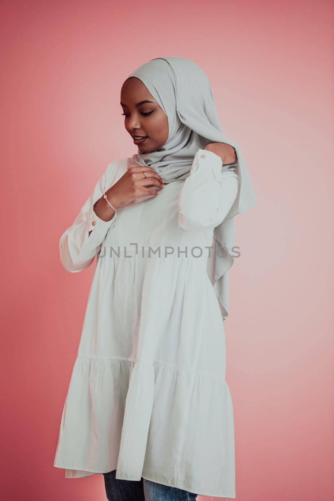 Portrait of young modern muslim afro beauty wearing traditional islamic clothes on plastic pink background. Selective focus. High quality photo