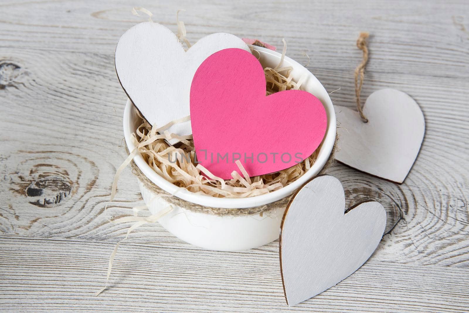 White and red wooden hearts in a ceramic bowl filled with paper. Place for your text