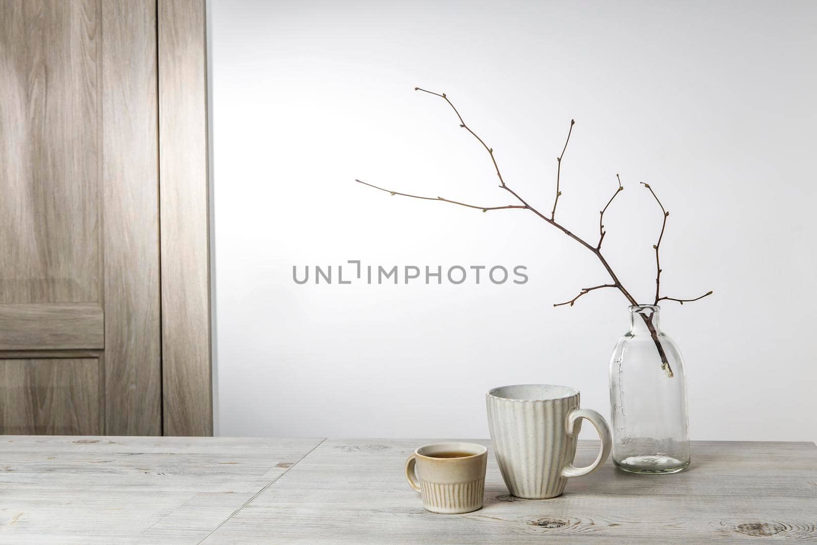 An unblown linden branch are in a glass vase and a small beige cup of coffee on the table. Scandinavian style. Place for your text