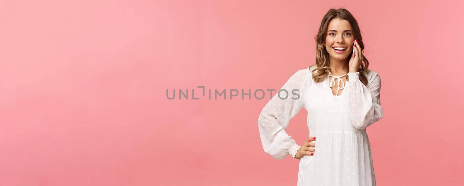 Portrait of joyful good-looking blond woman in white dress, talking on phone, hold smartphone near ear and look upbeat camera, smiling discuss friends date, stand pink background by Benzoix