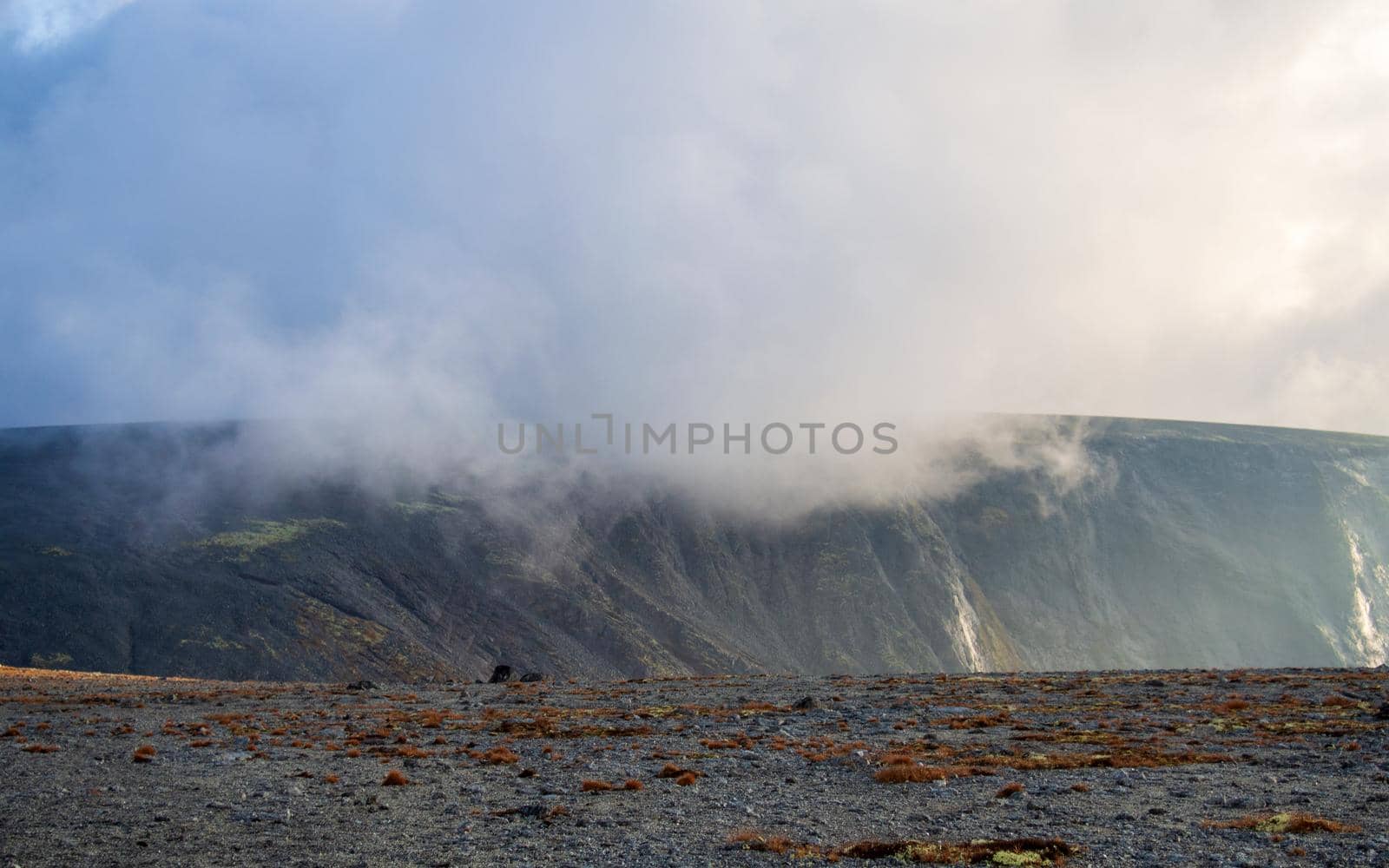 Autumn colorful tundra on the background mountain peaks in cloudy weather. Mountain landscape in Kola Peninsula, Arctic, Khibiny Mountains.