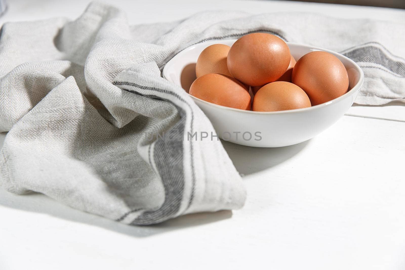 Brown chicken eggs in white mask, beige towel on the table. Copy space by elenarostunova