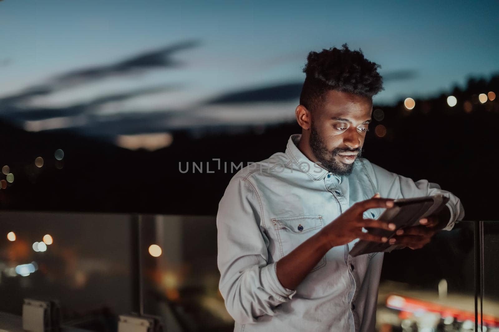 The young man on an urban city street at night texting on a smartphone with bokeh and neon city lights in the background. High-quality photo. High-quality photo