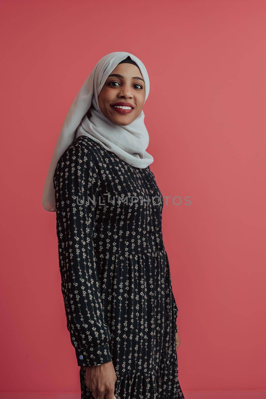 Portrait of young modern muslim afro beauty wearing traditional islamic clothes on plastic pink background. Selective focus. High quality photo