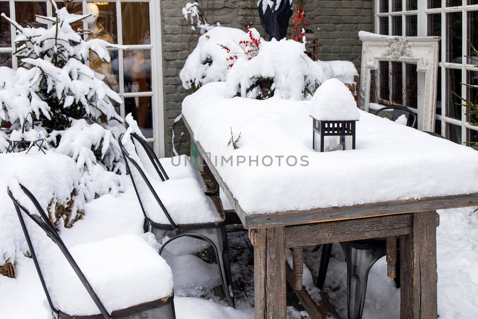 Snow-covered veranda, a table with a dried bouquet of branches with viburnum berries by elenarostunova