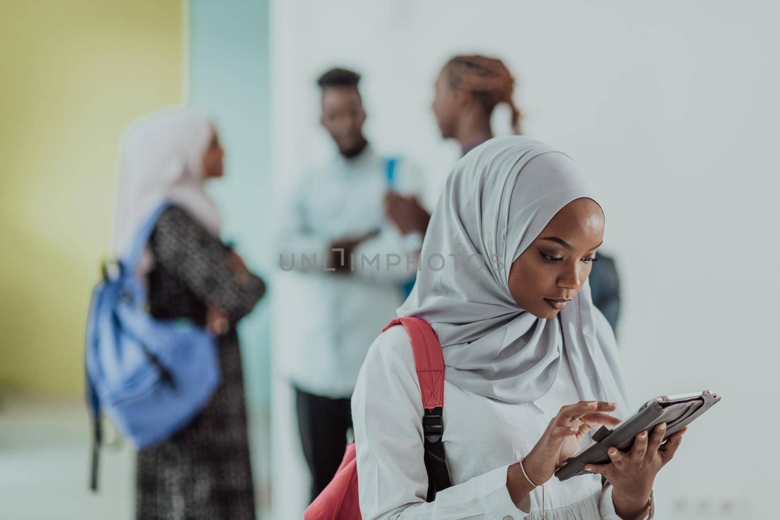 African female student with a group of friends in the background wearing traditional Islamic hijab clothes. Selective focus. High-quality photo