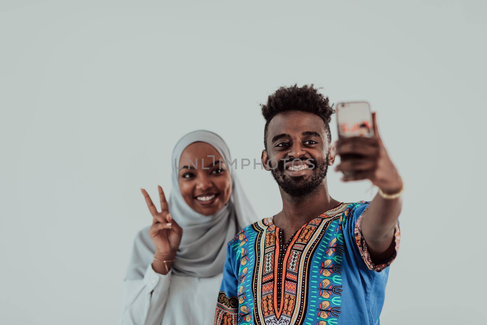 A young African couple taking a selfie on their smartphone, my shoes in traditional Sudan clothes. Selective focus. High-quality photo