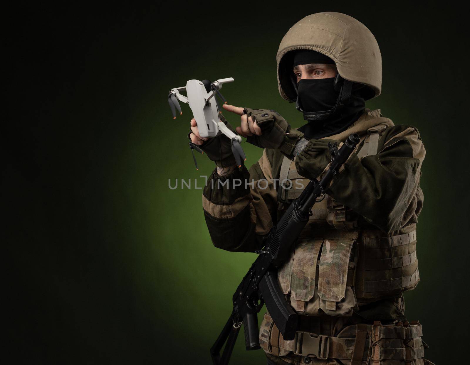 soldier in military clothes with a weapon launches a small unmanned quadcopter for reconnaissance on a dark background