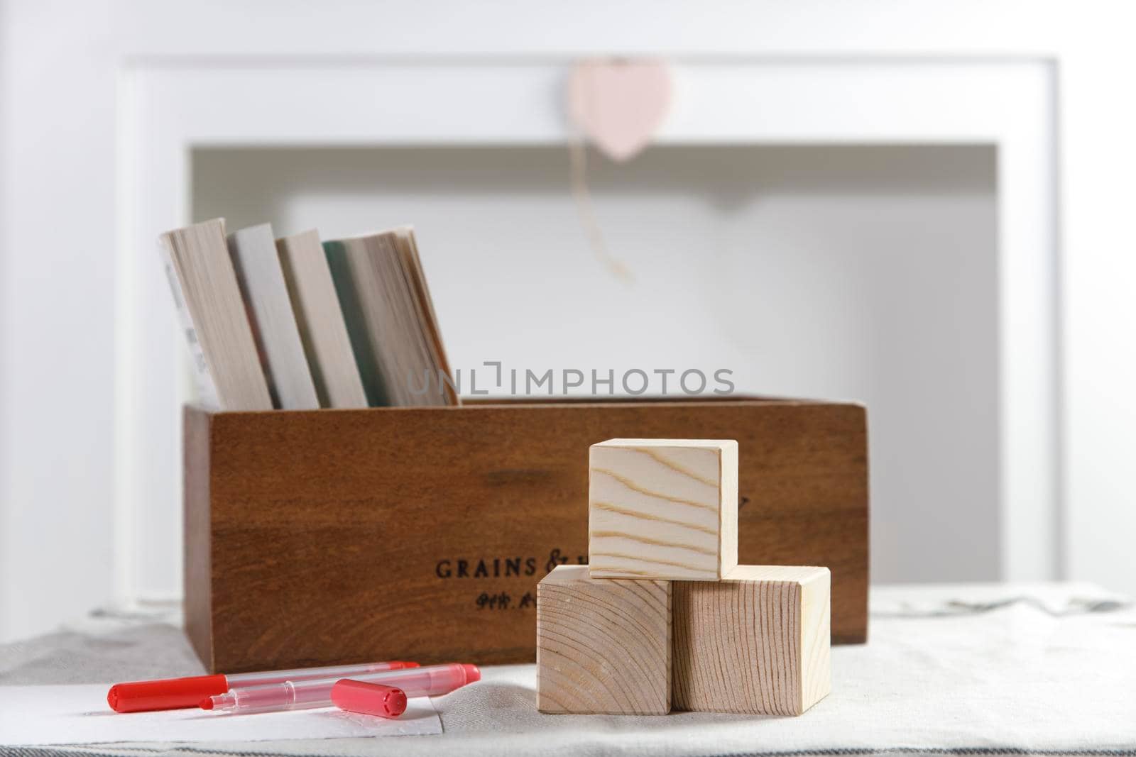 Wooden container with books, three cubes on the table against the background of a white fireplace. Place for text. Valentine's Day