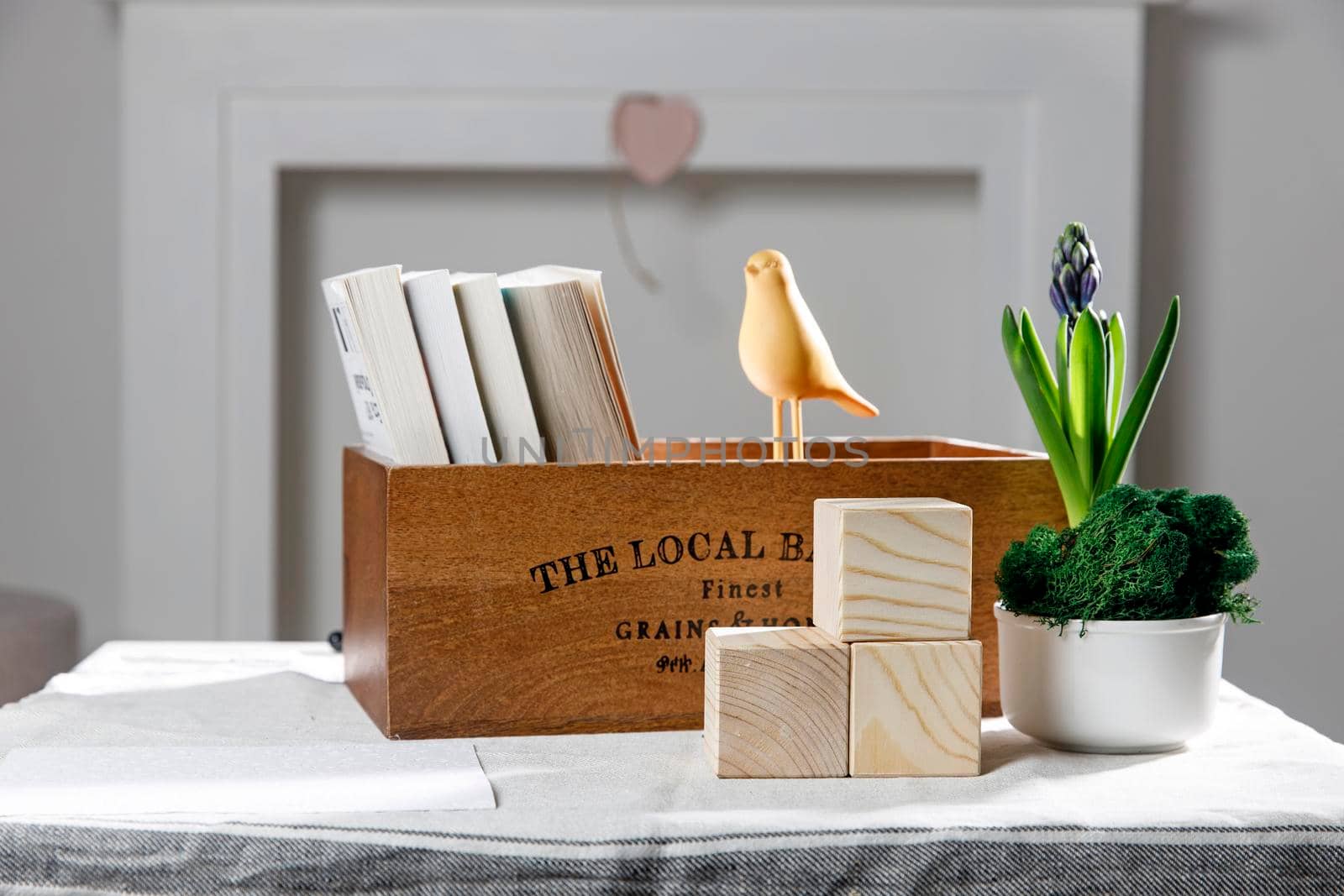 Wooden container with books, three cubes on the table against the background of a white fireplace. Place for text. Valentine's Day