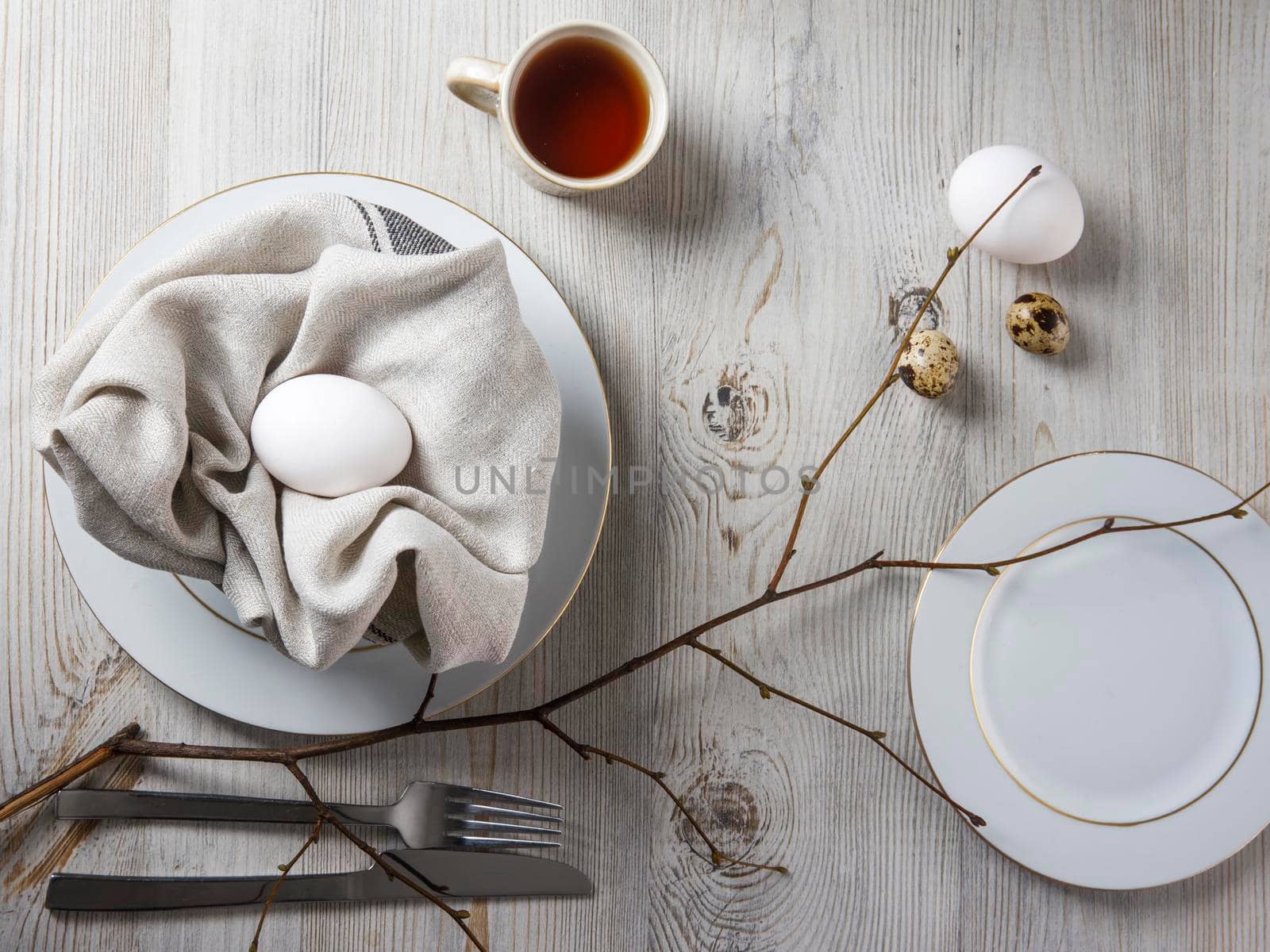 Table setting and decoration for Easter. White and partridge eggs in a plate with a napkin. poplar unblown branch by elenarostunova