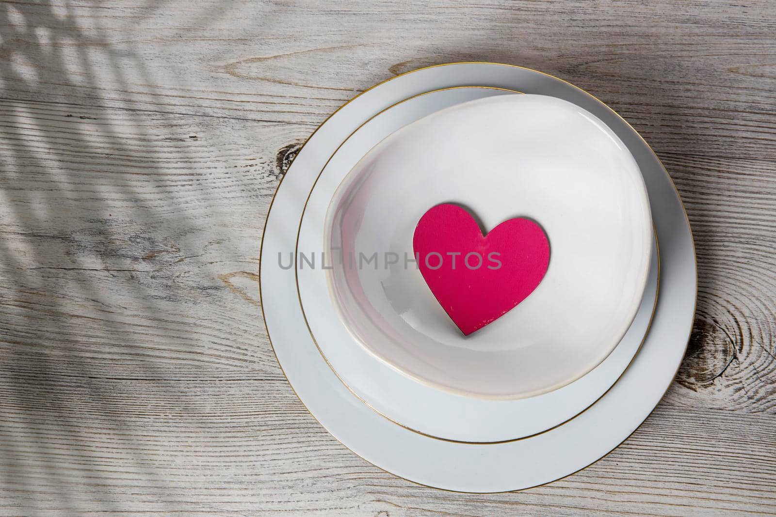Red wooden hearts in a ceramic bowl filled with paper. Place for your text by elenarostunova