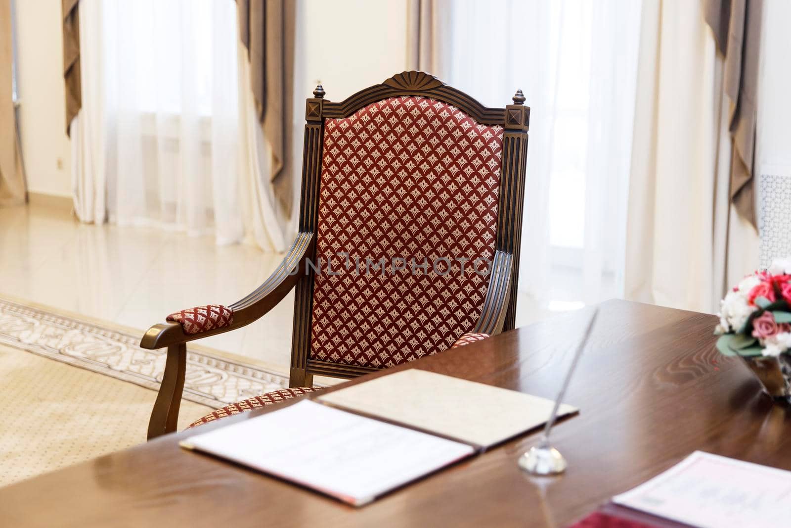 Standard wedding registration hall in Moscow. A red armchair in the Empire style at the wooden table, where the spouses sign the act of registering the wedding.