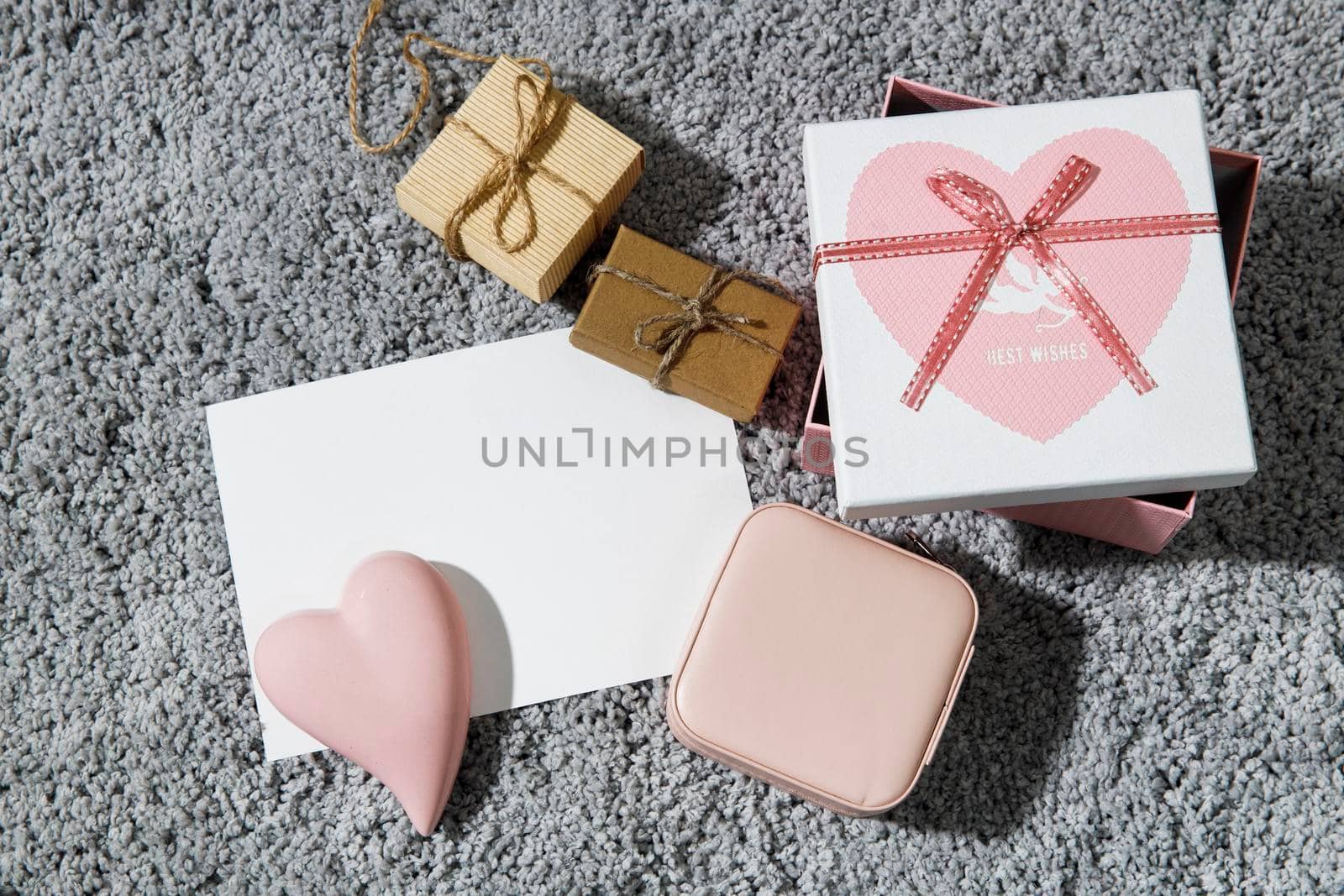 Greeting card for Valentine's Day. Envelopes, wrapped boxes, ceramic pink heart on a grey fluffy carpet background. Copy space. Place for text by elenarostunova