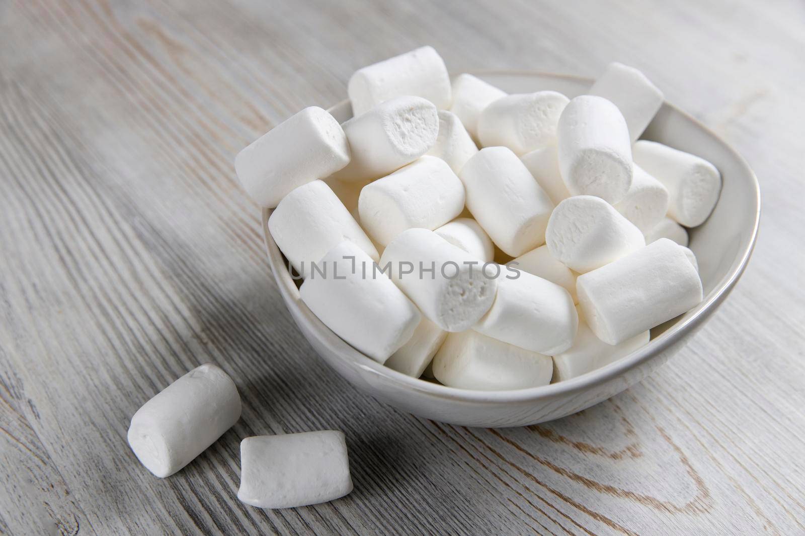 White marshmallows in a porcelain bowl on the table by elenarostunova