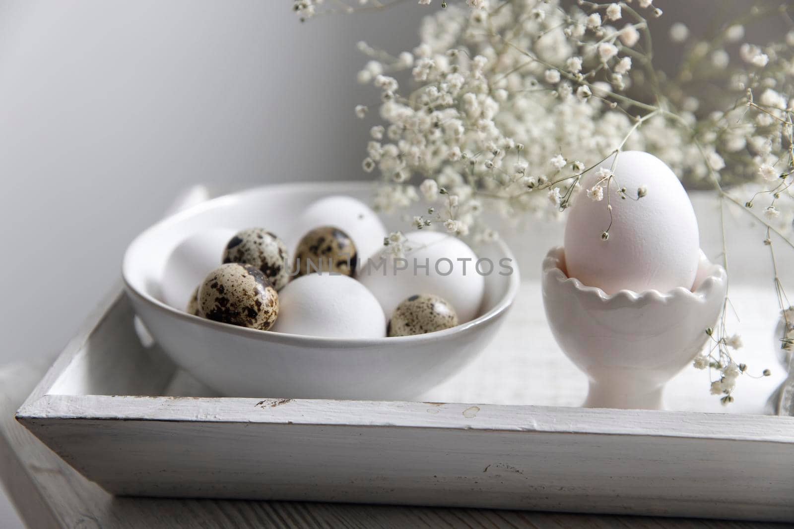 Table decorated for Easter in beige tones. Dried gypsophila, chicken and quail eggs and a cup of coffee. Easter concept.