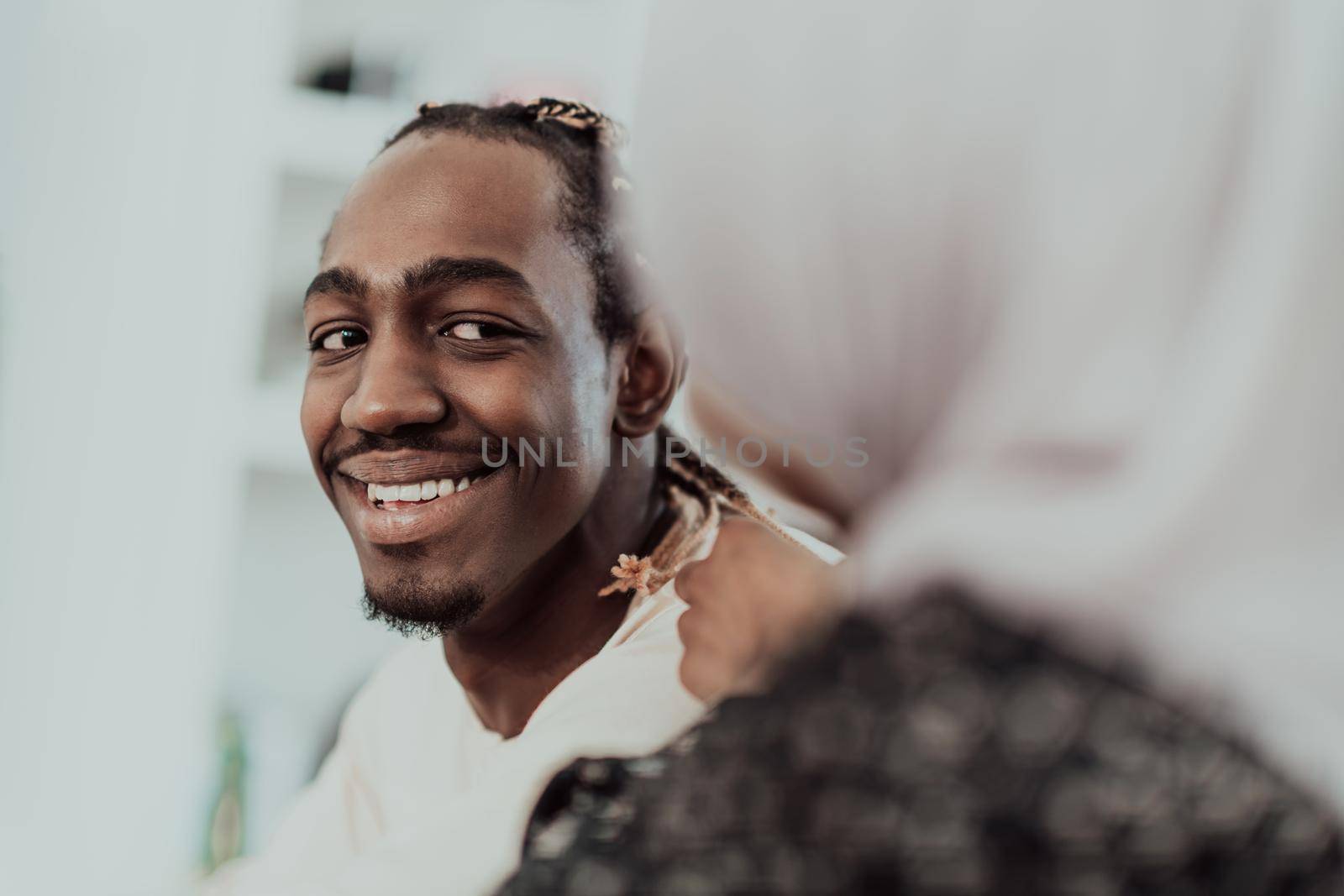 A young Muslim couple has a romantic time at home while the woman makes the hairstyle for her husband female wearing traditional Sudan Islamic hijab clothes. by dotshock