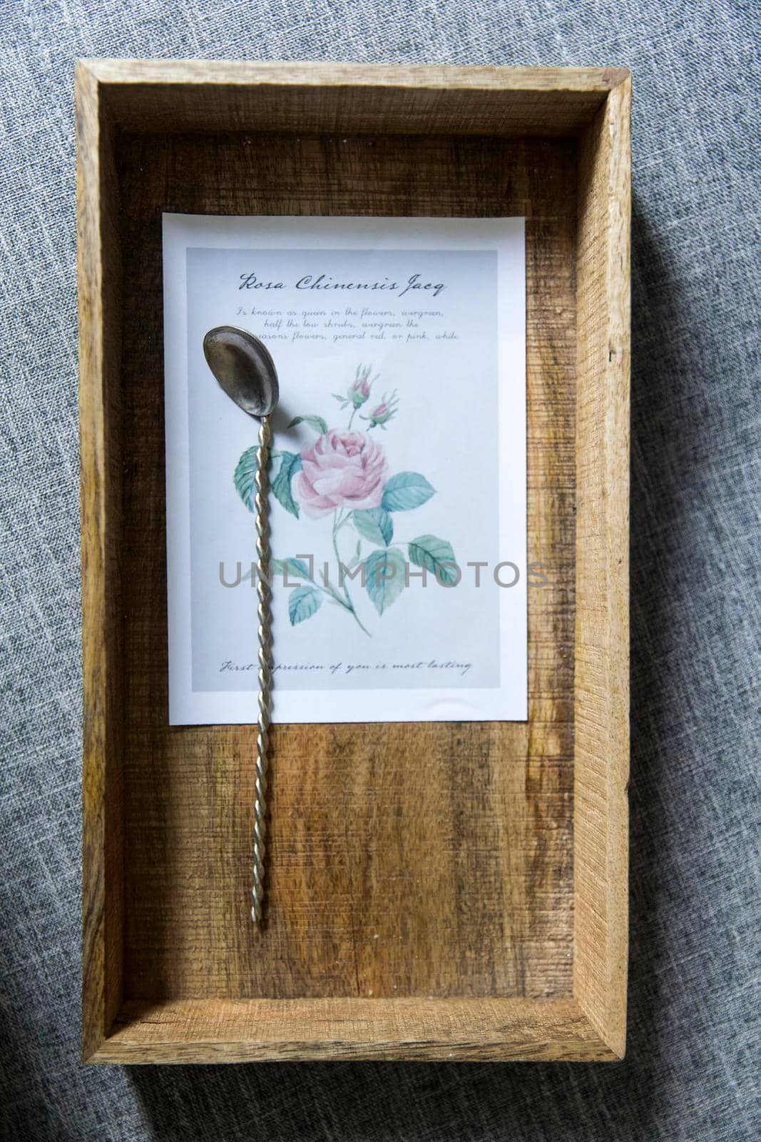 A long twisted dessert spoon lies on a wooden tray in the picture with a flower. Still life. Copy space