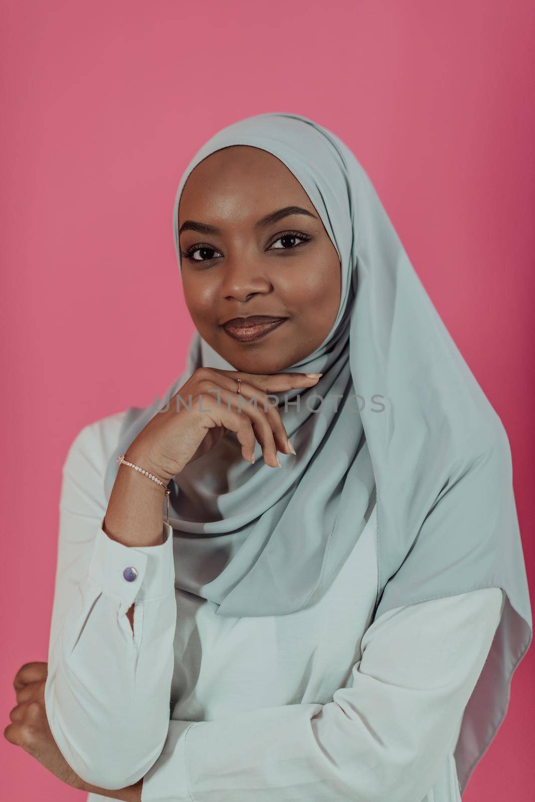 Portrait of young modern muslim afro beauty wearing traditional islamic clothes on plastic pink background. Selective focus. High quality photo