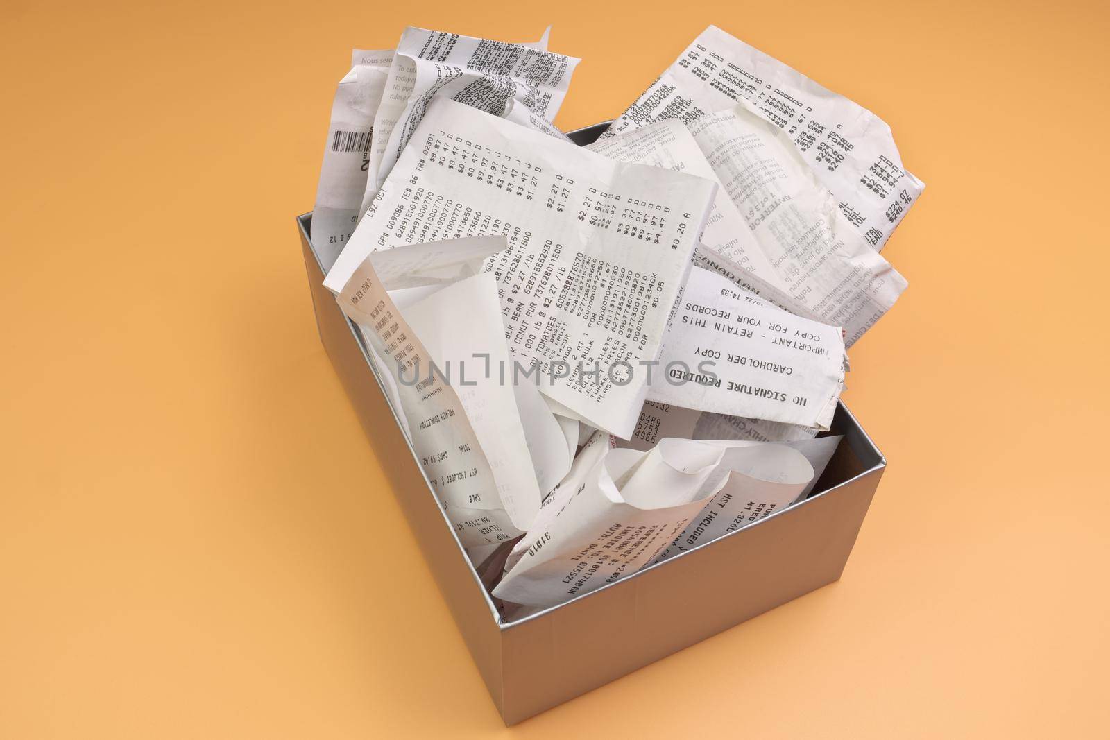 An Overflowing Box of Receipts Ready for Accounting, Bookkeeping, or tax filing Isolated on an Orange Yellow Background