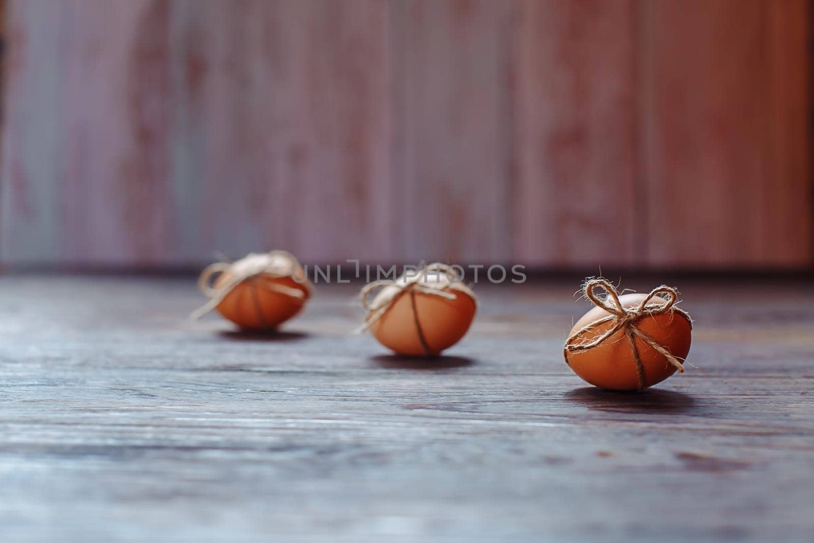 Easter beige eggs decorate with rope on brown wooden background with copyspace