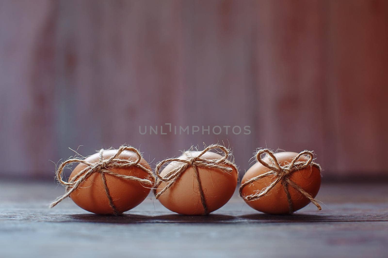 Easter beige eggs decorate with rope on brown wooden background with copyspace