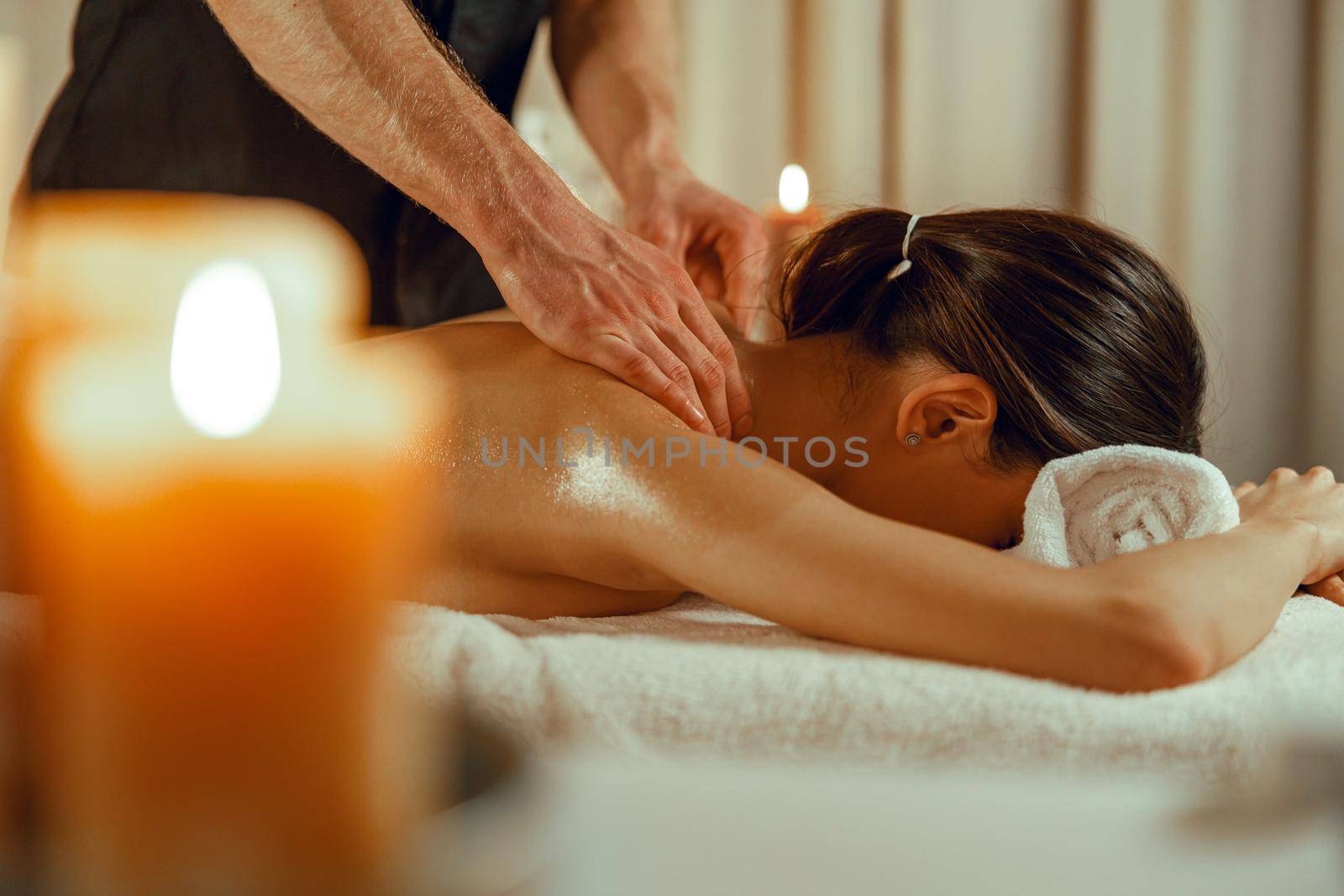 Woman relaxing while masseur doing spine back massage at beauty spa resort. Treatment