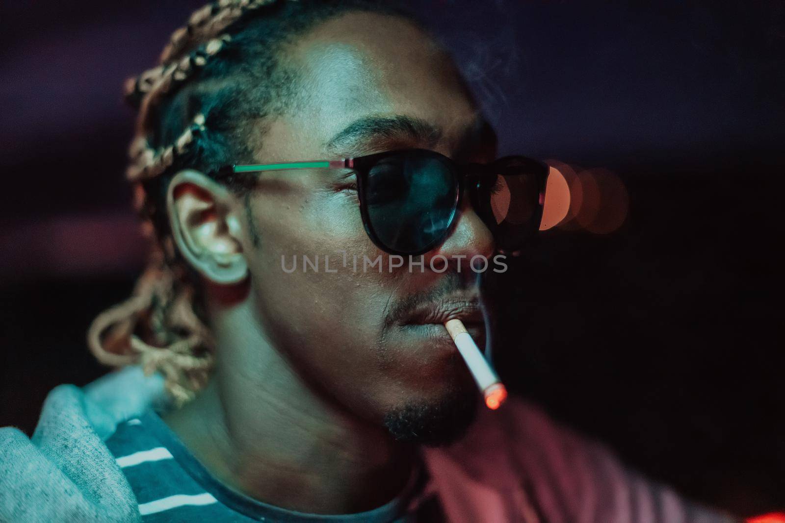 Afro Americans smoking a cigar, in the background city lights. High quality photo