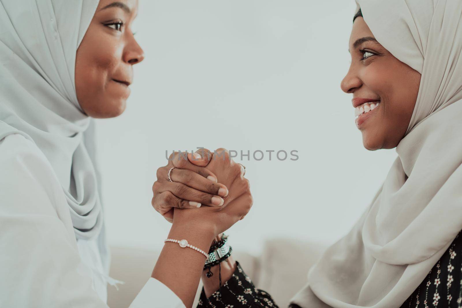 African woman arm wrestling conflict concept, disagreement and confrontation wearing traditional islamic hijab clothes. Selective focus by dotshock