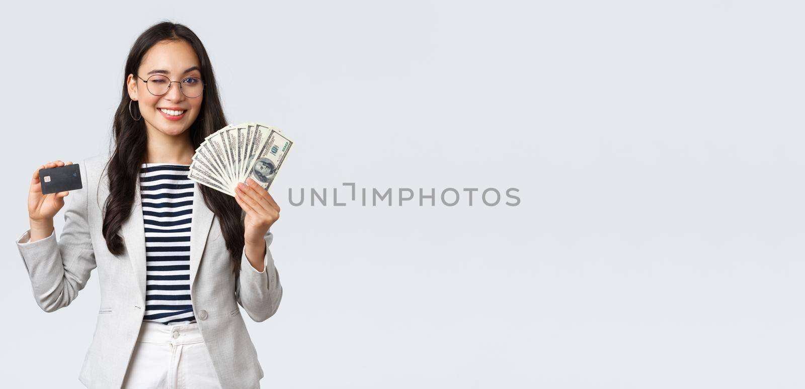 Business, finance and employment, entrepreneur and money concept. Successful asian businesswoman showing explain on courses how increase income, hold credit card and money, smiling camera by Benzoix