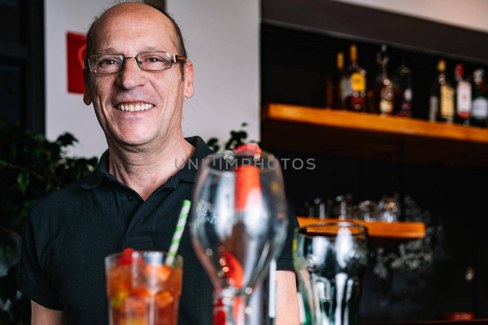 portrait of a mature waiter carrying a tray of beverages by CatPhotography