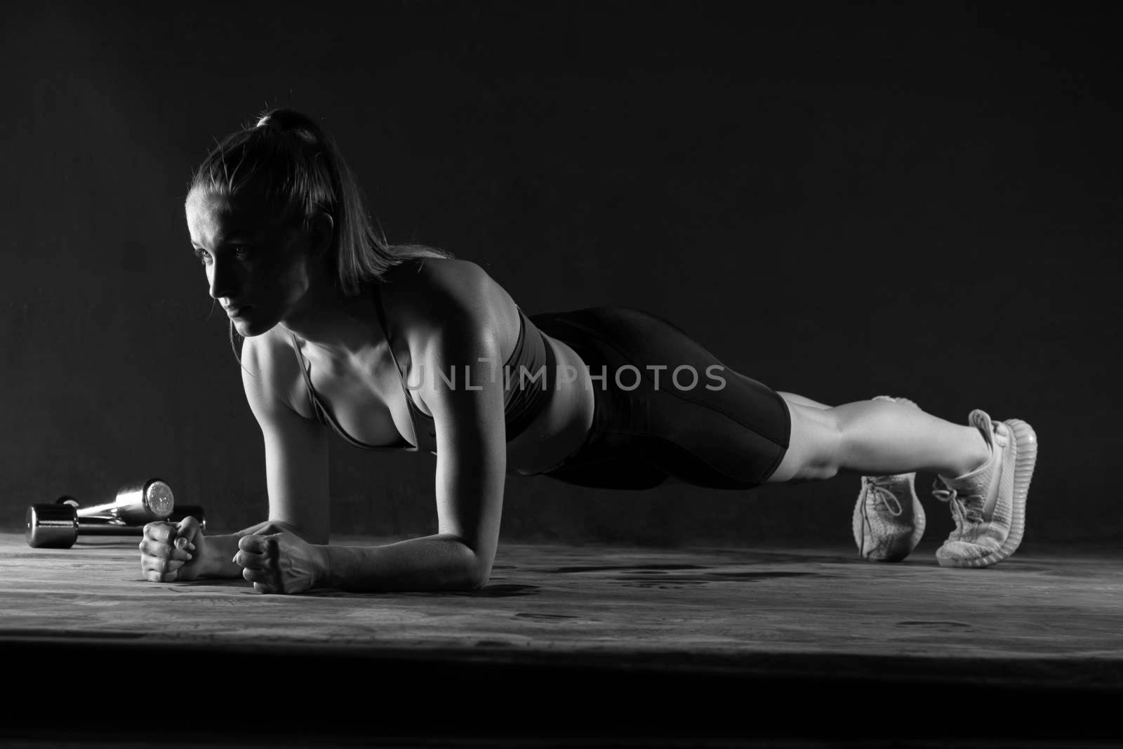 The bar in a girl black on lies a background girl dumbbells plank body, from gym health for young for sport trainer, beautiful biceps. Slim ABS weight, power smile push-ups