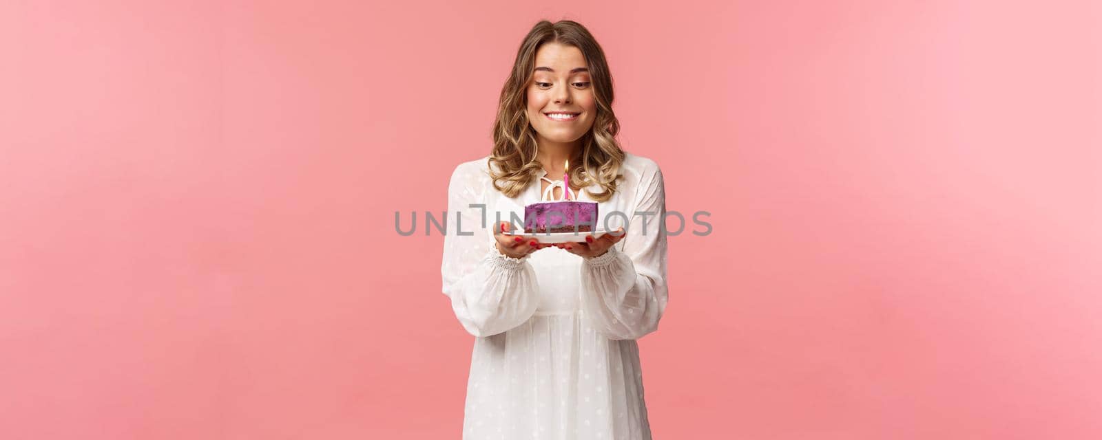 Holidays, spring and party concept. Portrait of dreamy, happy birthday girl feeling excitement and joy celebrating b-day, biting lip and smiling as making wish blowing candle on cake by Benzoix