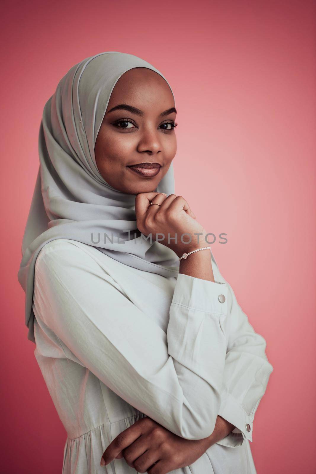 Portrait of young modern muslim afro beauty wearing traditional islamic clothes on plastic pink background. Selective focus. High quality photo