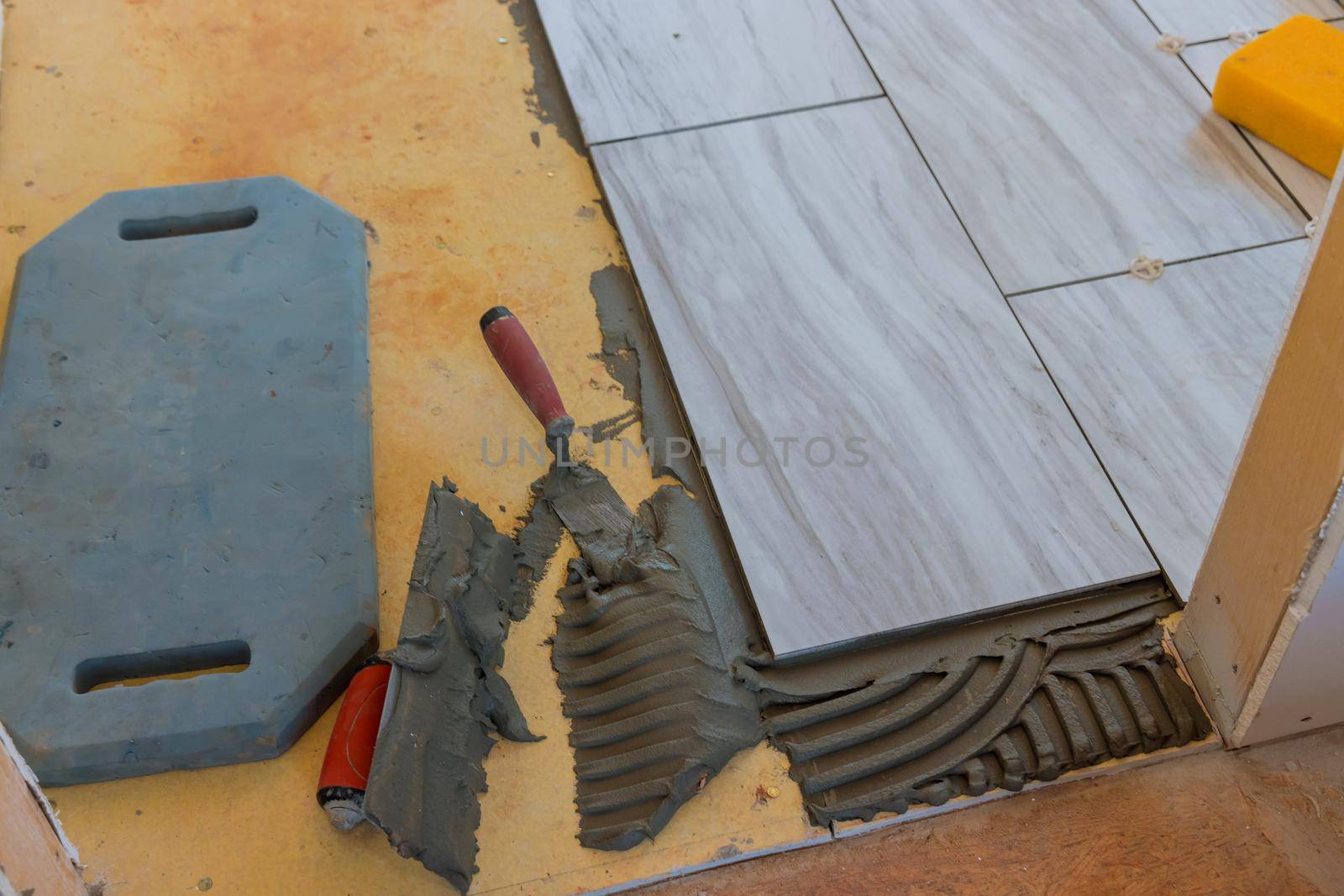 Tiler builder worker installing floor tile at repair renovation work