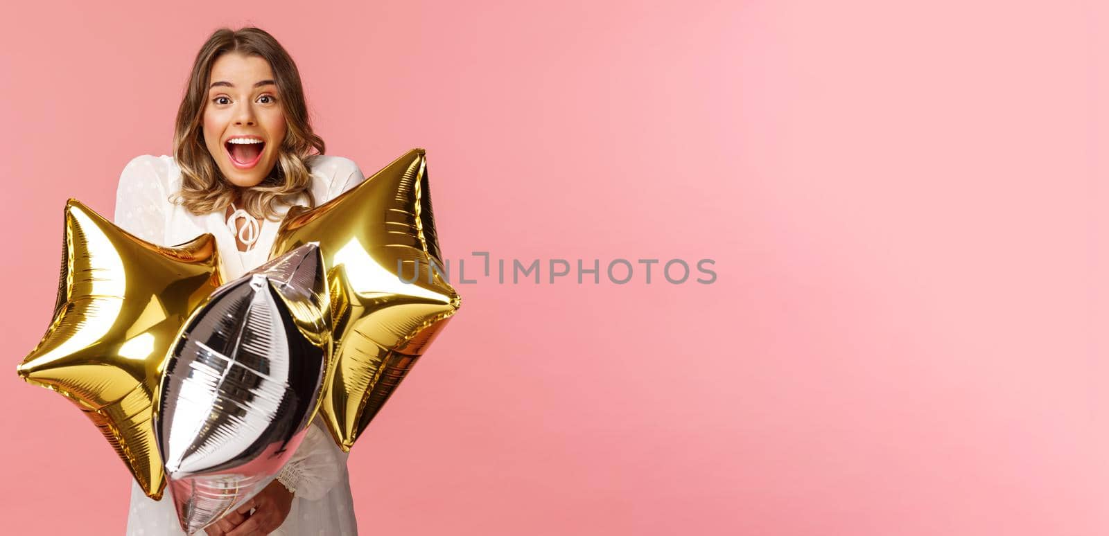 Holidays, celebration and women concept. Happy charming and surprised girl being congratulated with birthday, holding star-shaped balloons and smiling joyfully camera, pink background by Benzoix