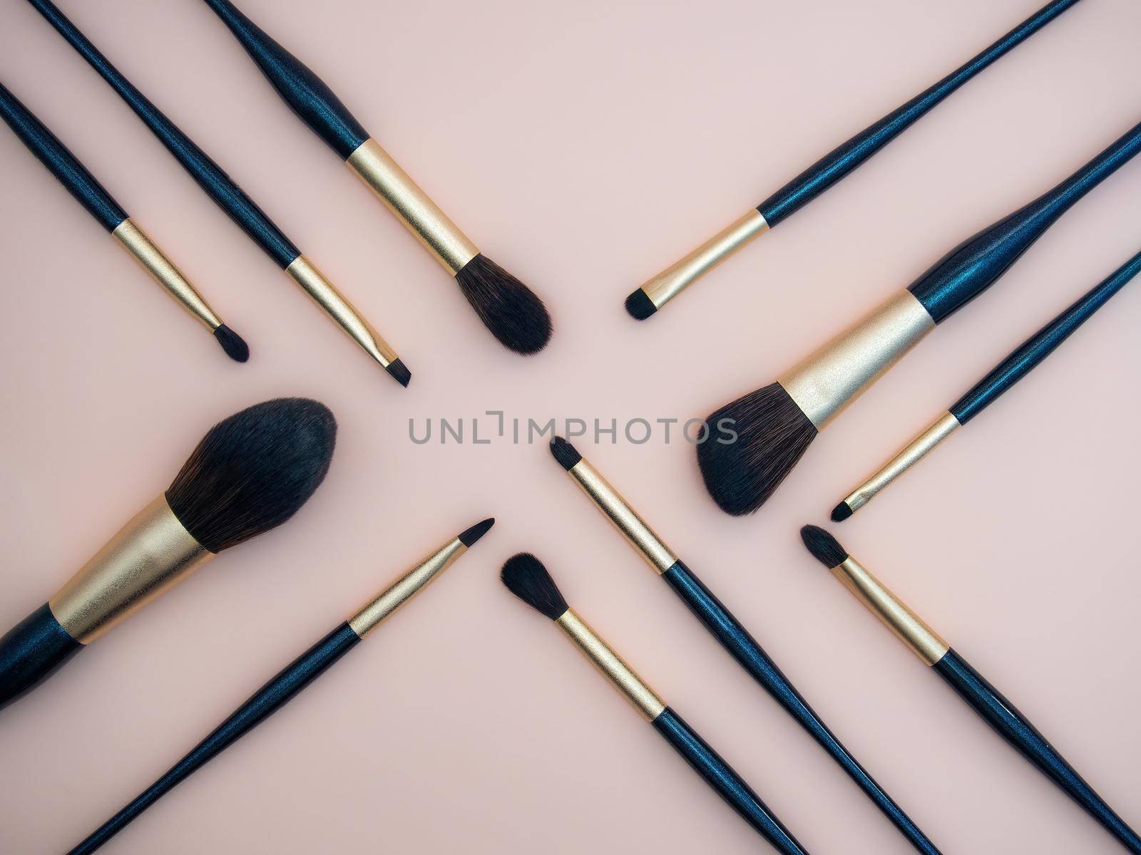 Assortment of female make-up of various face brushes. A set of professional dark blue and golden makeup brushes on a pink background. photo