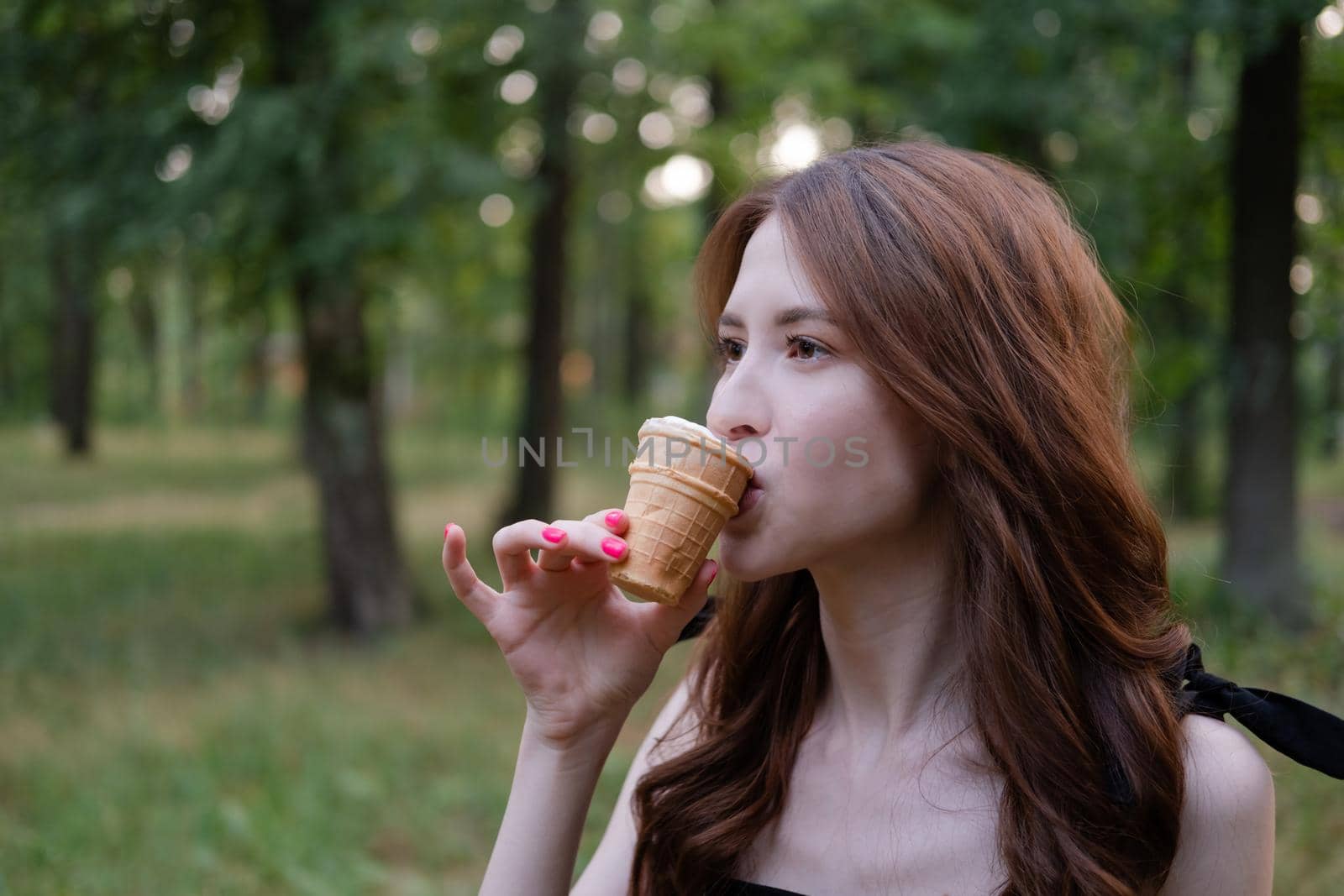 Smiling cheerful ukrainian brunette young woman eating ice cream outdoors.