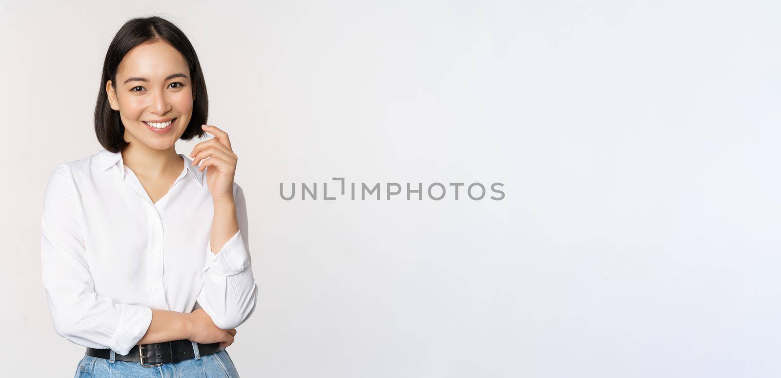 Young asian woman, professional entrepreneur standing in office clothing, smiling and looking confident, white background.