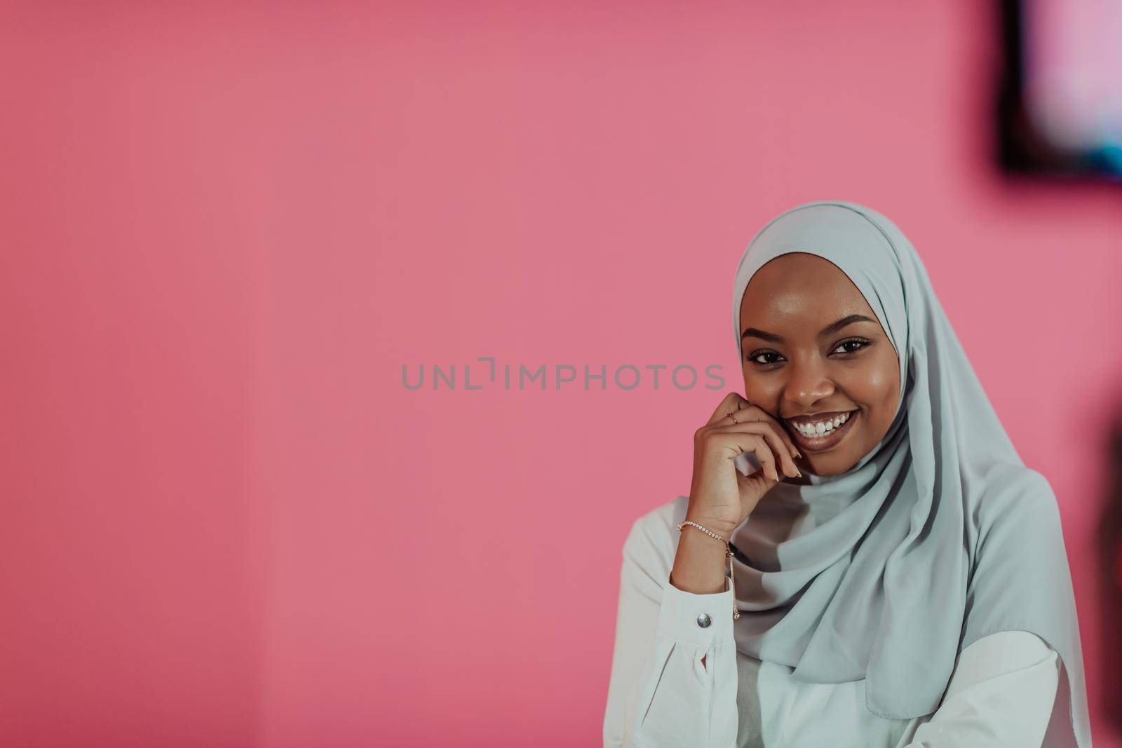 Portrait of young modern muslim afro beauty wearing traditional islamic clothes on plastic pink background. Selective focus. High quality photo