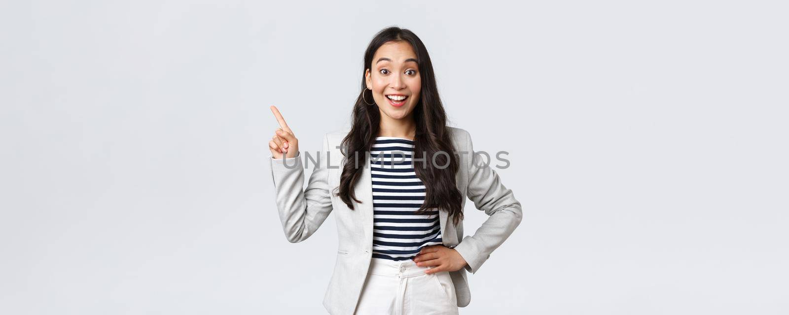 Business, finance and employment, female successful entrepreneurs concept. Cheerful successful businesswoman in white suit pointing fingers upper left corner, showing advertisement.