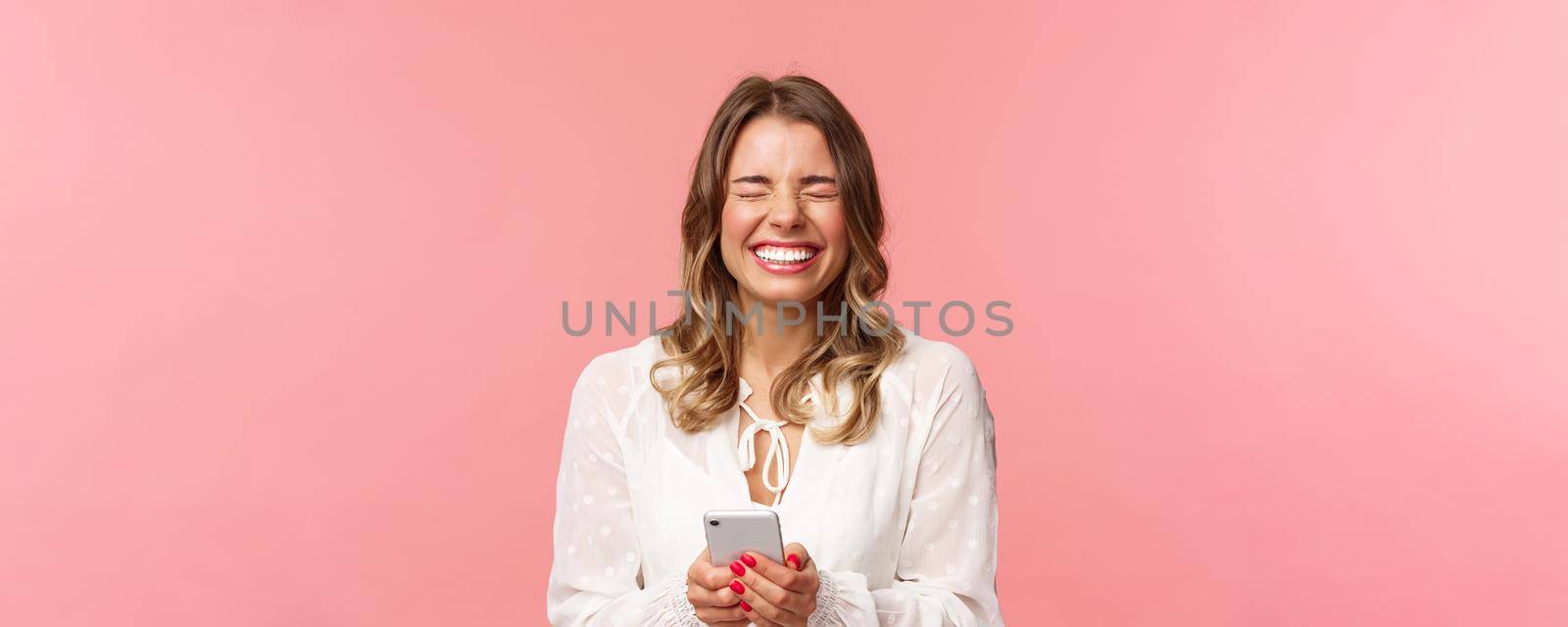 Close-up portrait of carefree tender, lovely blond girl in white dress, laughing over funny joke or message, holding mobile phone, close eyes and giggle at something hilarious, pink background by Benzoix