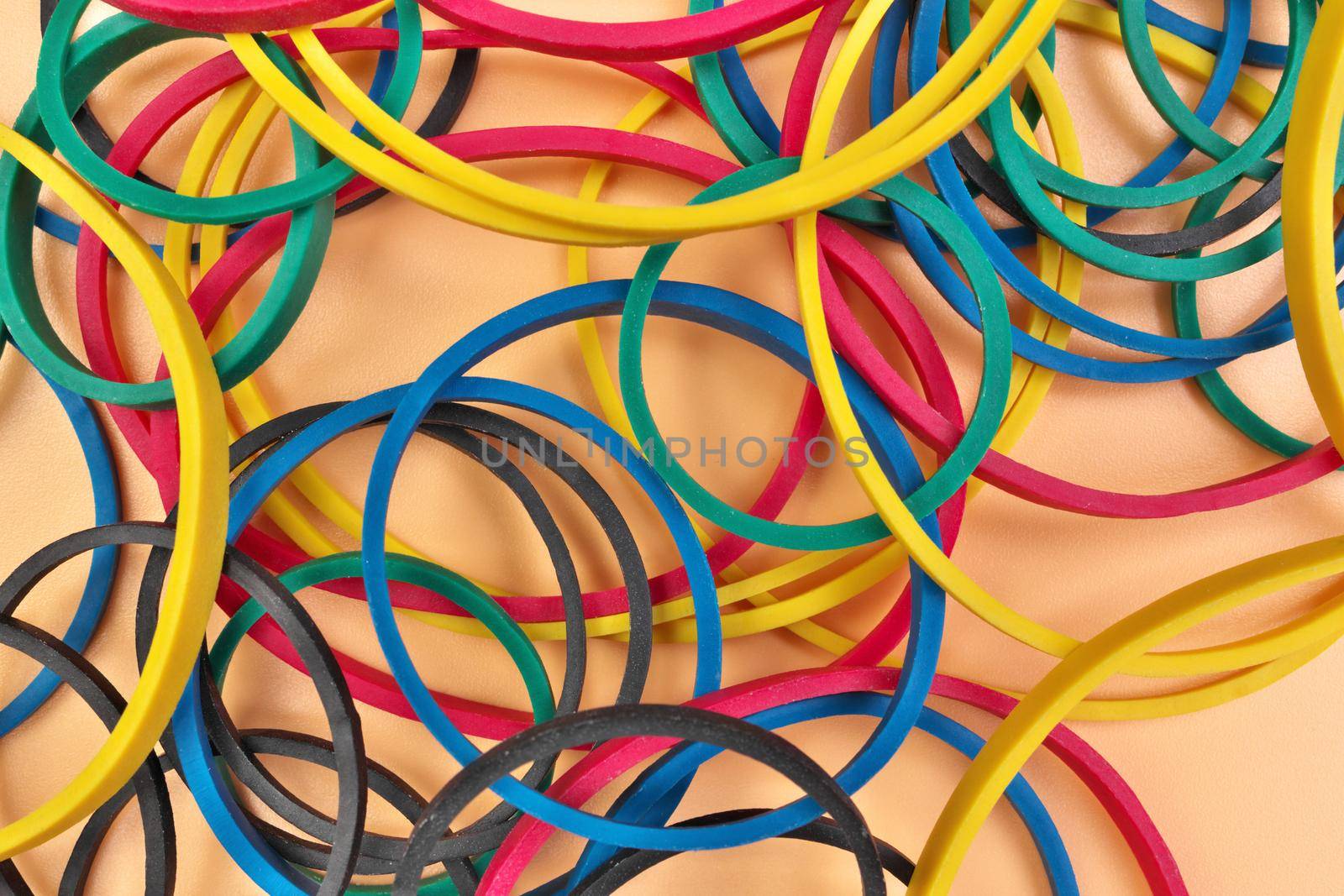 Full Frame Image Flatlay of Multicolored Elastic Rubber Bands on a Cheerful Orange Pastel Background by markvandam