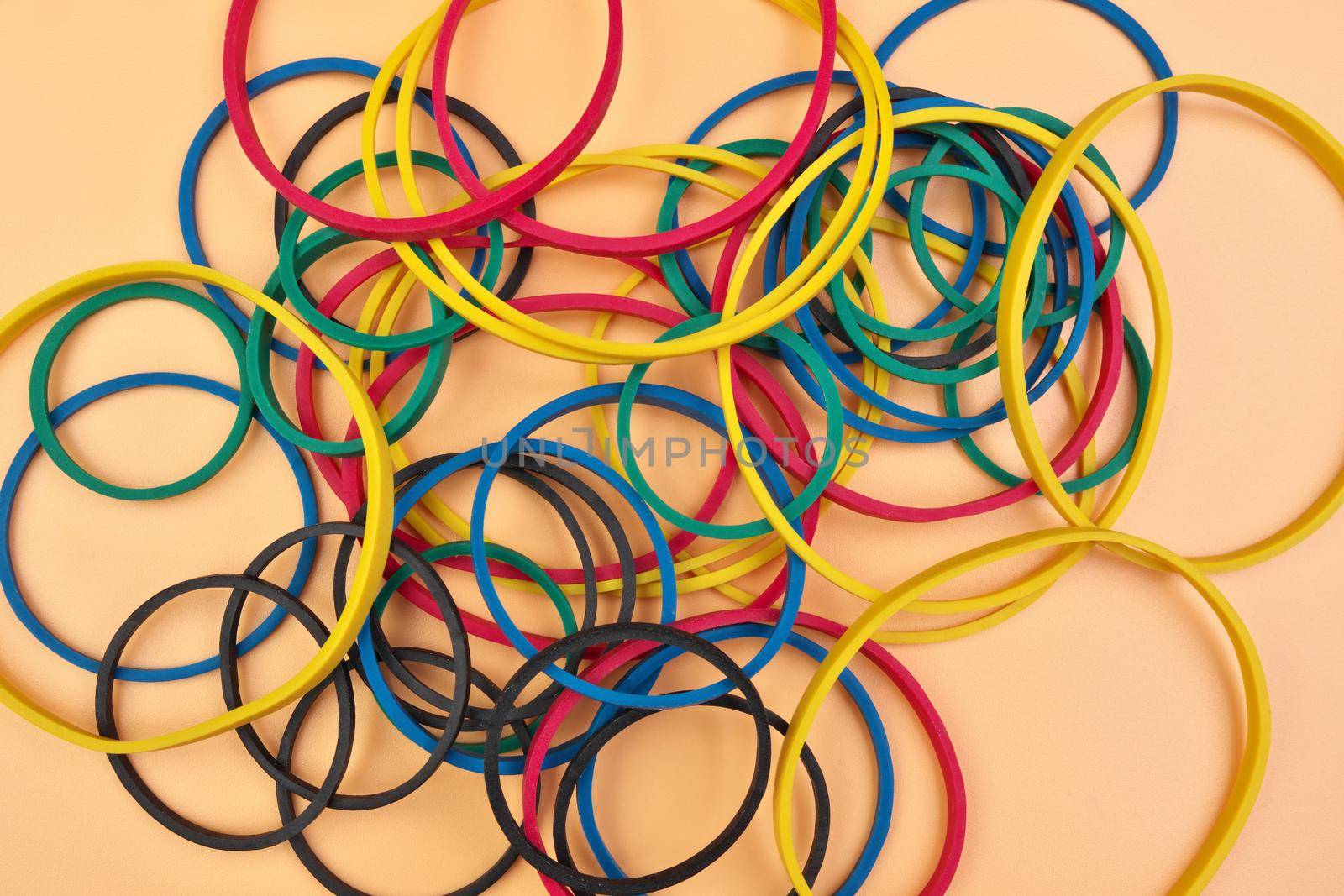 Full Frame Image Flatlay of Multicolored Elastic Rubber Bands on a Cheerful Orange Pastel Background by markvandam