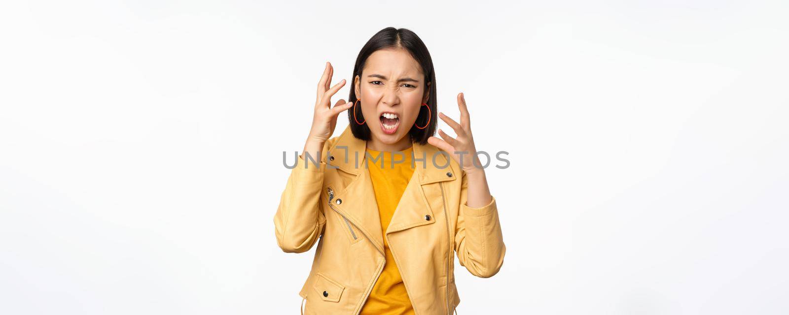 Asian angry woman arguing, shaking hands angry and screaming, shouting with frustrated face, standing over white background.