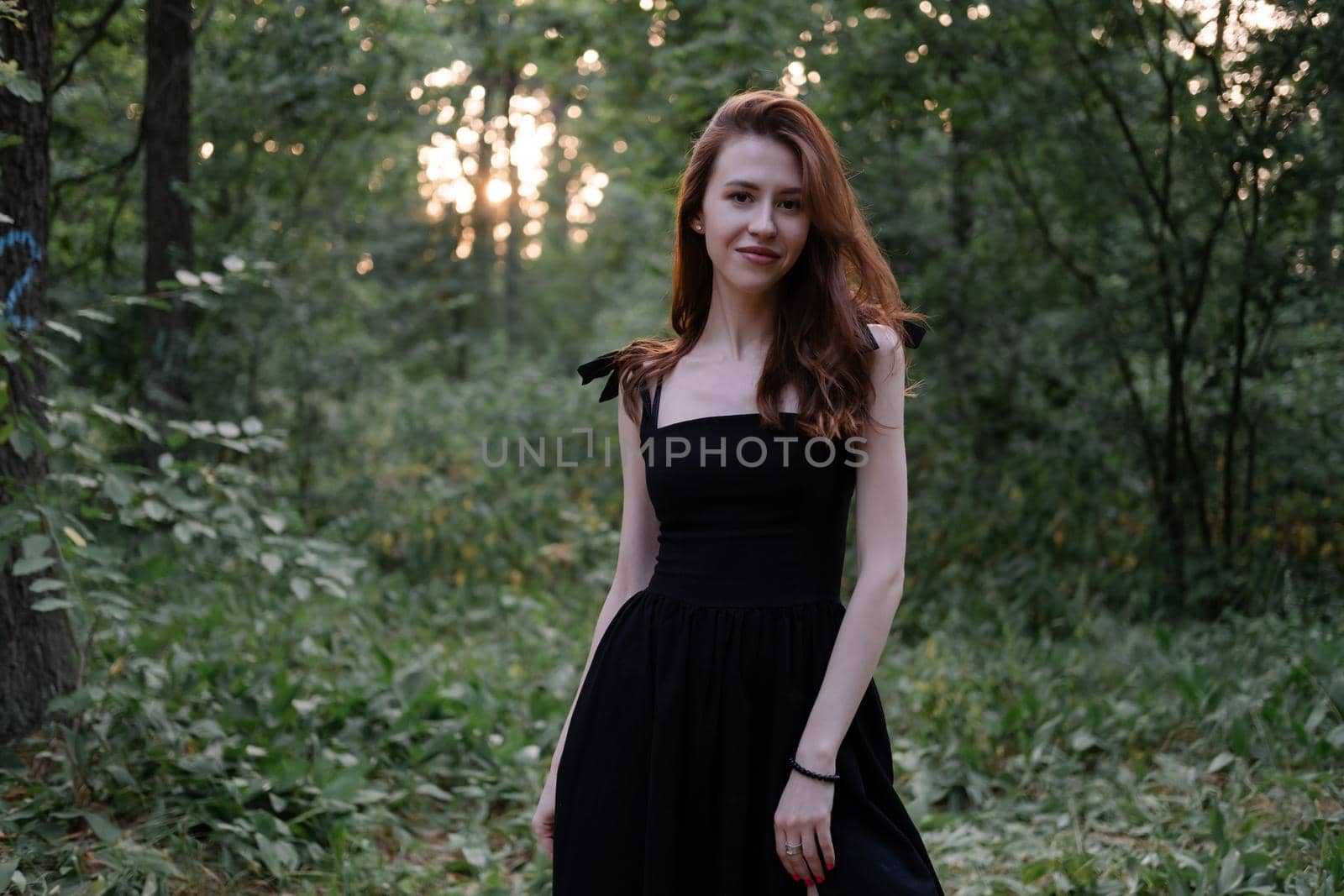 portrait of sensual young woman in a black dress in the forest. freedom, loneliness. nature loving.