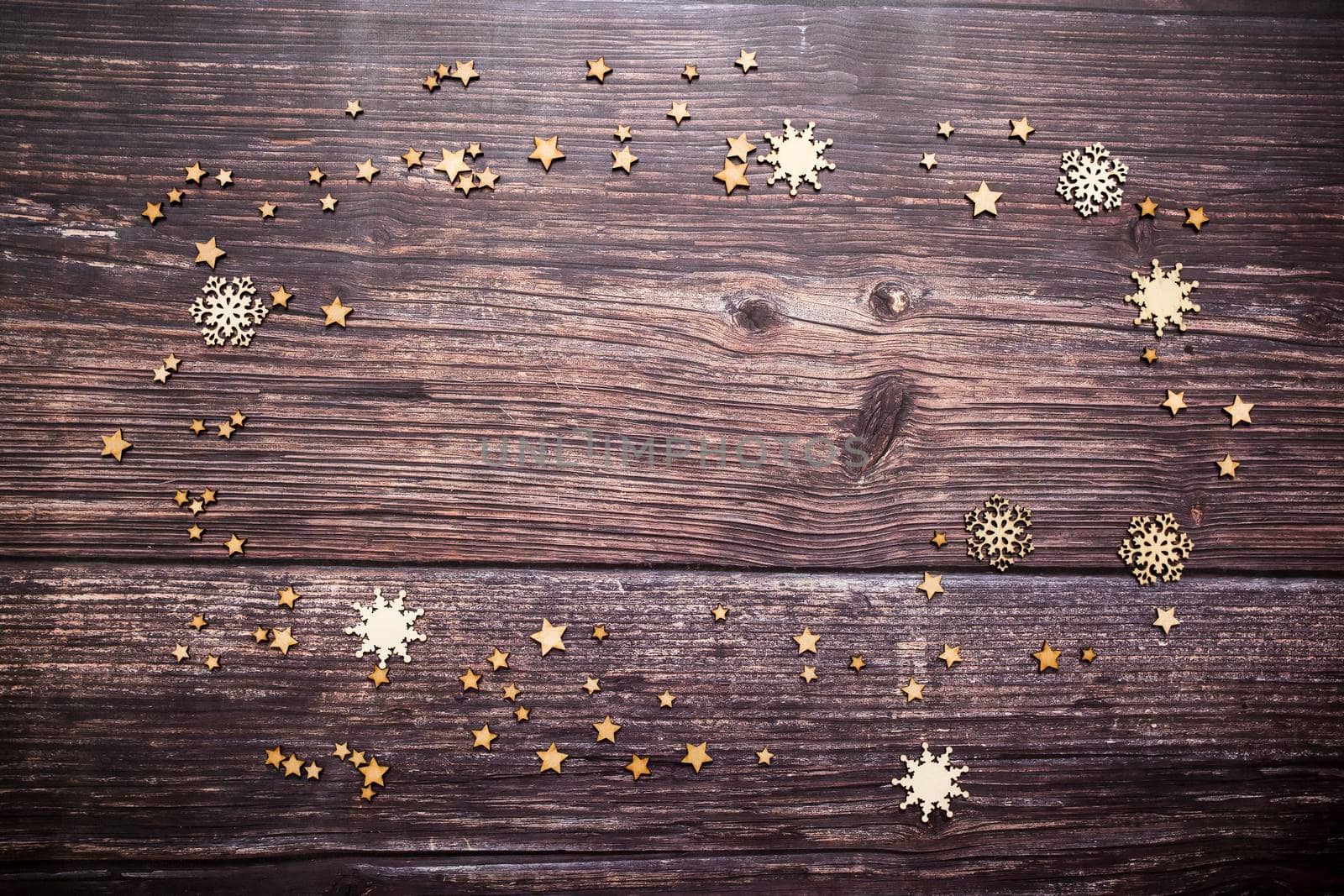 Stars and snowflakes of various sizes are scattered on a wooden table. Place for text. Copy space by elenarostunova